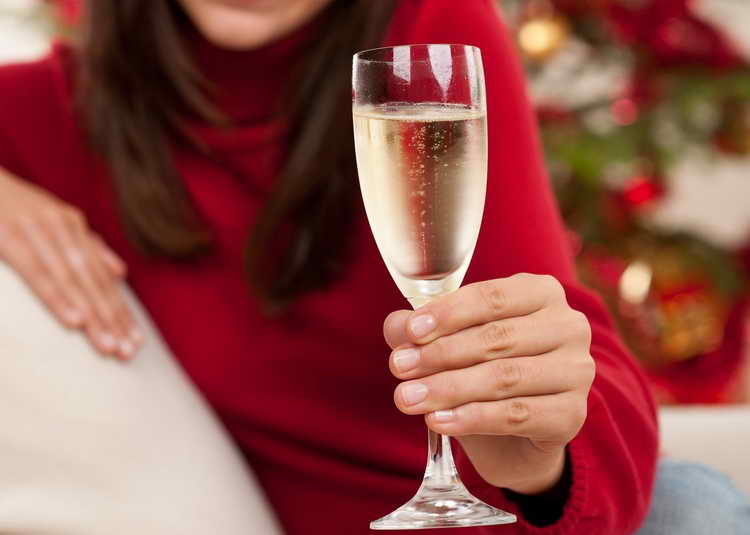 brown-hair-woman-sitting-with-glass-of-champagne-on-christmas-in-front-of-tree